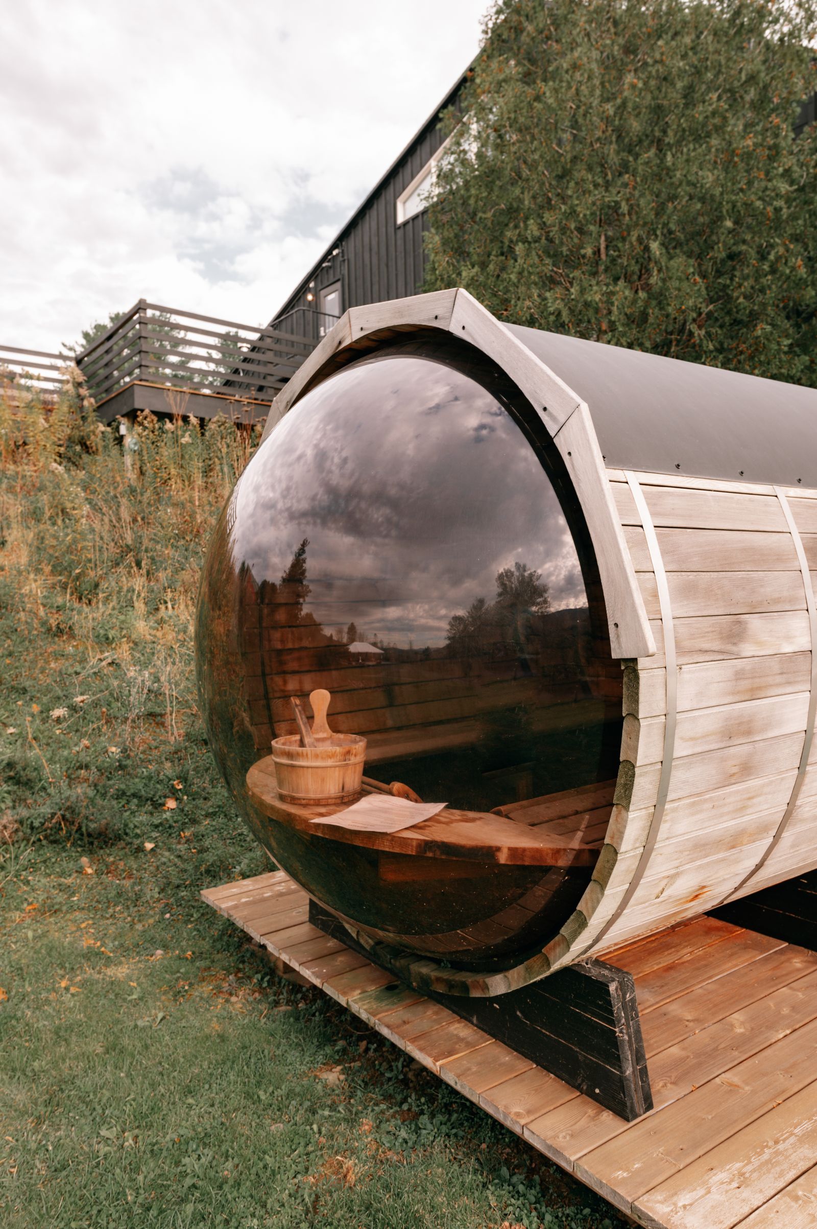 A barrel sauna tucked into a green backyard